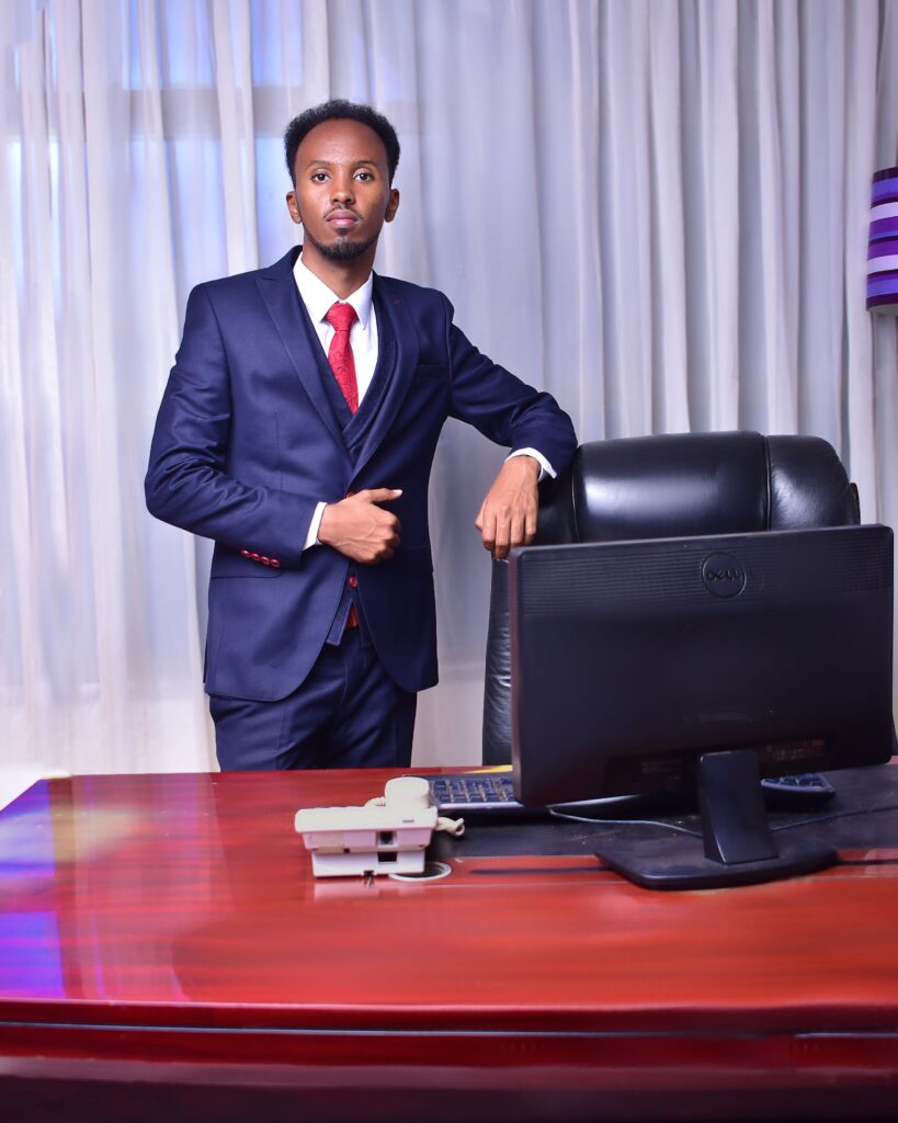 A professional businessman in a suit standing confidently at his office desk.